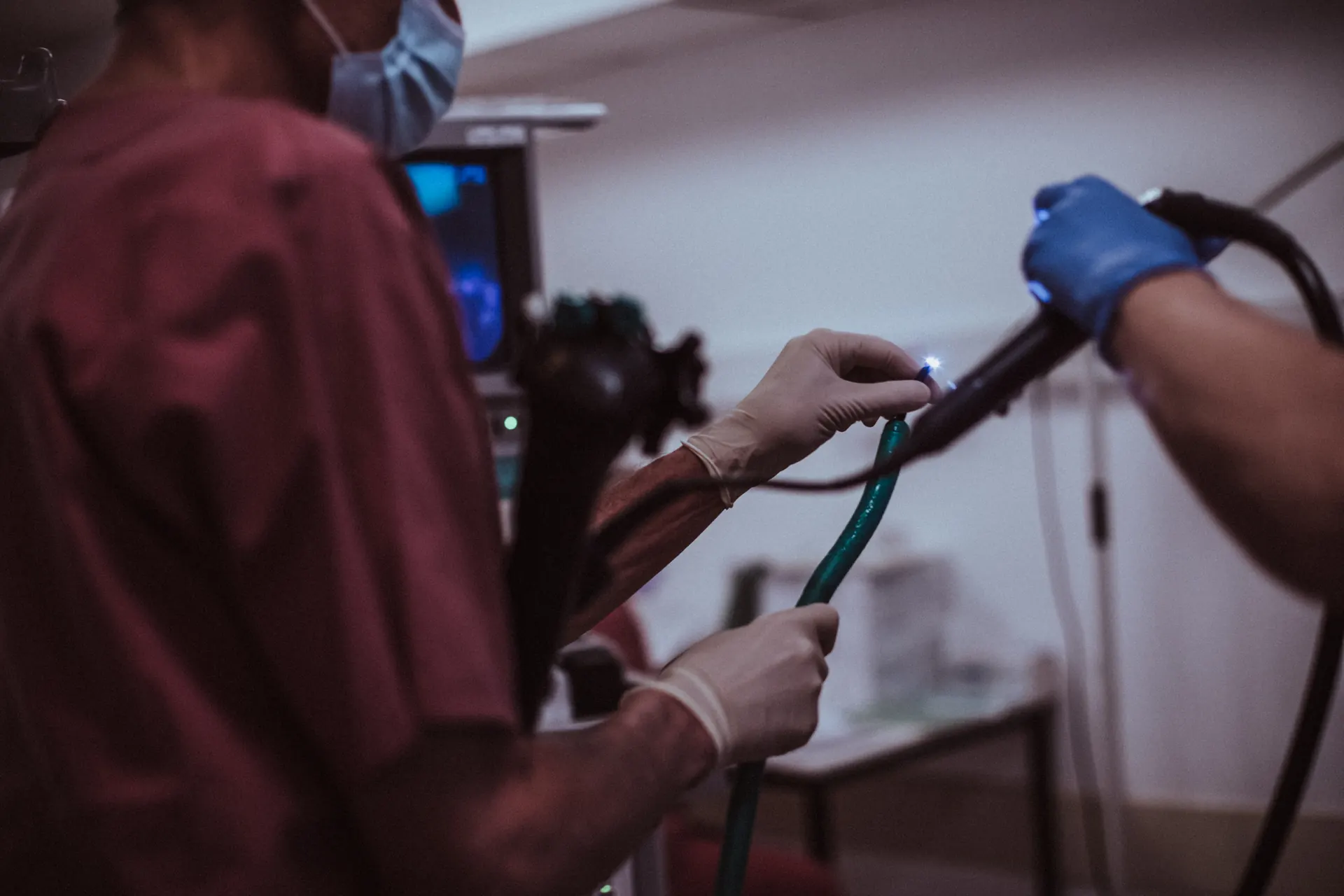Mani guantate guidano un endoscopio, sullo sfondo il monitor