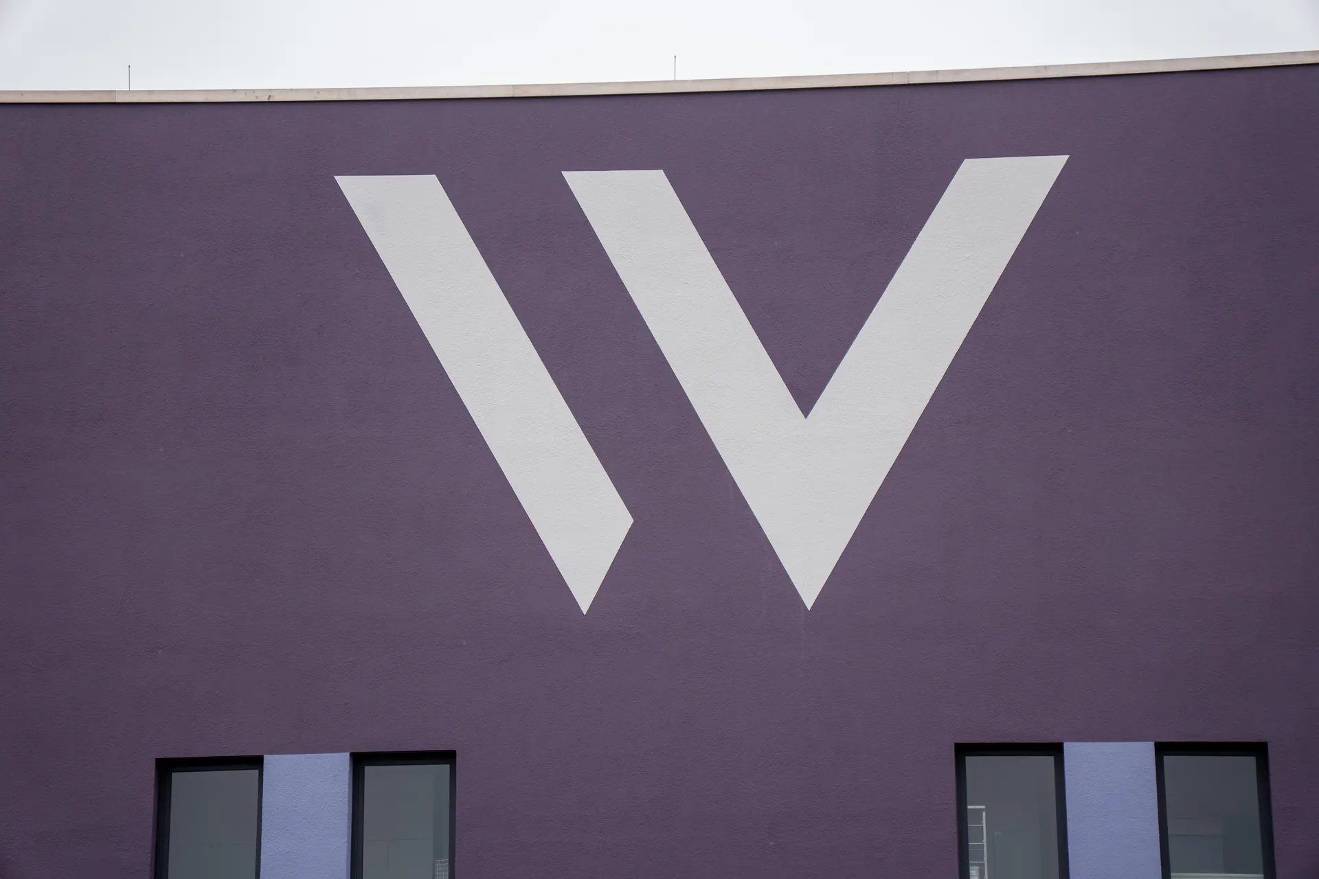 Grande W bianca sulla facciata viola della Weight Doctors® Nationalklinik di Wertheim